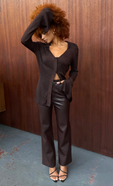 model is wearing brown leather trousers with a brown fitted cardigan