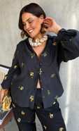 model is wearing the gold snake black shirt and matching trousers with a gold clutch and a chunky shell necklace