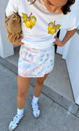 close up of our lemon boob t-shirt tucked into a white mini jaspre skirt and pared with some ankle socks and trainers