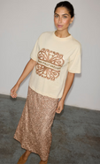 model is wearing the cream logo t-shirt with the gold sequin dorris midi skirt