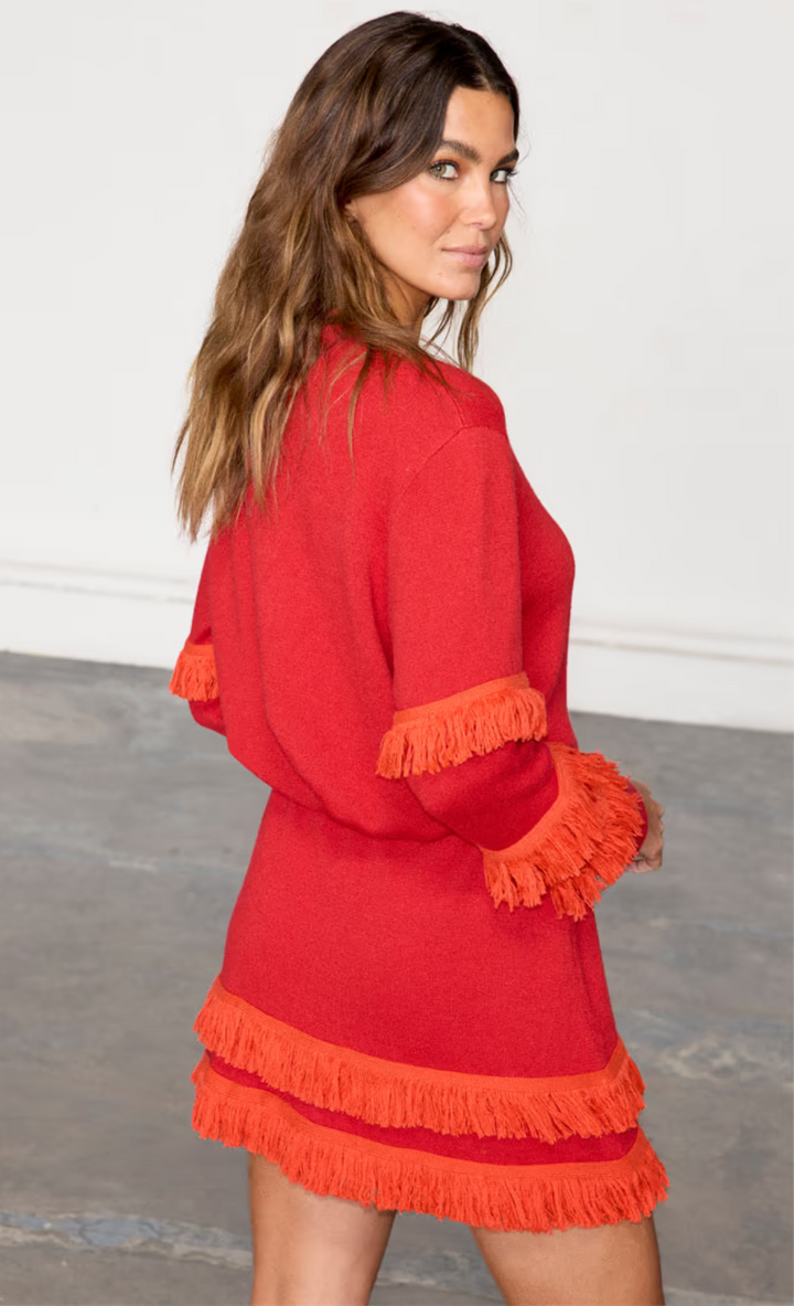 model is wearing the red holly cardigan and matching mini skirt with orange fringing
