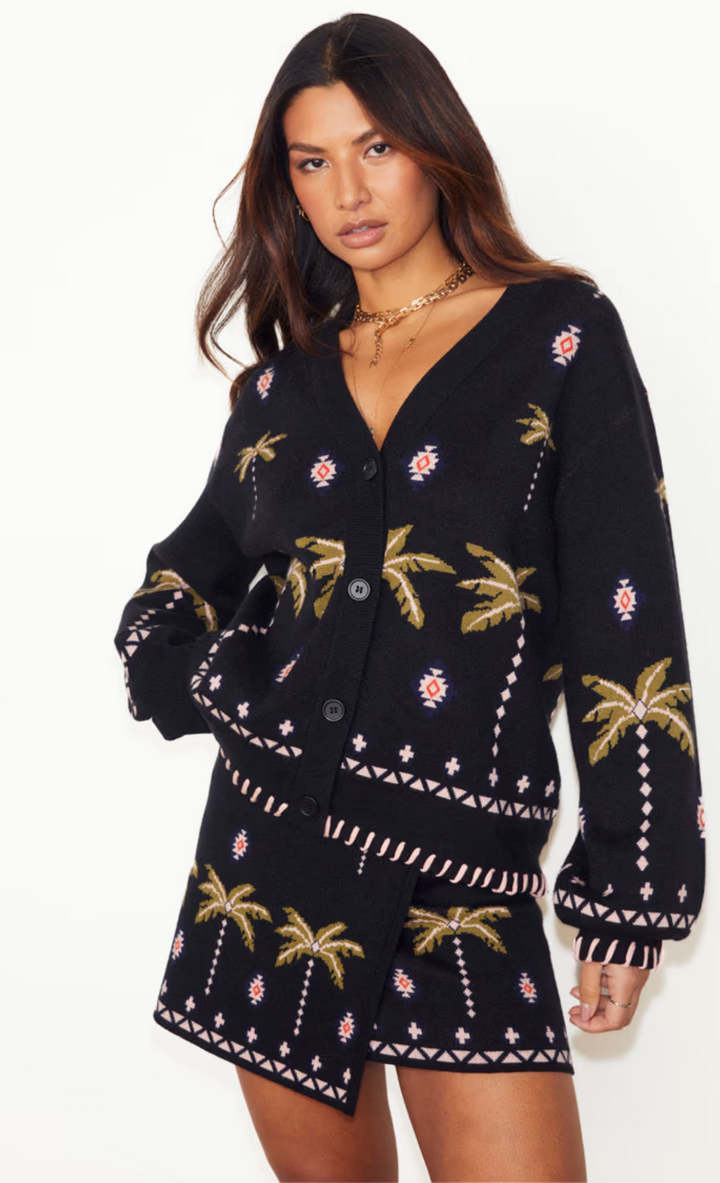 model is wearing palm leaf design cardigan with matching mini wrap skirt